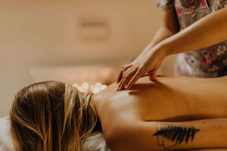 Une femme profite d'un massage relaxant pour les soins dans un spa resort tamisé et chaleureux.